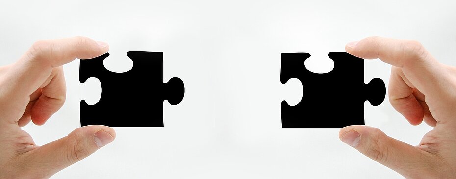 Zwei Puzzleteile in den Händen, die zusammenpassen