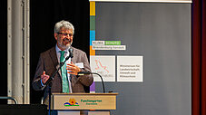 Person spricht lächelnd am Rednerpult des Familiengartens Eberswalde, im Hintergrund Roll-up des Ministeriums für Landwirtschaft, Umwelt und Klimaschutz Brandenburg