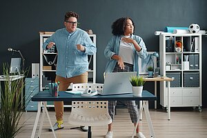 Zwei Personen machen eine Pause im Büro und bewegen sich.