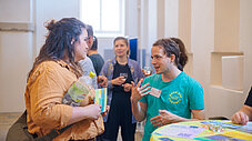 Zwei Personen im Gespräch an einem Ausstellungsstand, weitere Personen im Hintergrund