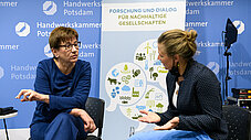 Zwei Personen im Gespräch vor Bannern der Handwerkskammer Potsdam und RIFS