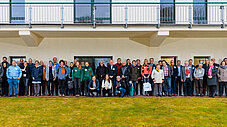 Große Gruppe von Teilnehmenden steht für ein Gruppenfoto vor einem Gebäude im Freien