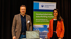 Ein Mann und eine Frau stehen am Stand der Handwerkskammer Potsdam vor einem Banner zu Wirtschaftsförderung, Umwelt und Technologie, auf dem Tisch ein Laptop.