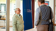 Frau am SEND-Ausstellungsstand im Gespräch mit einem Besucher