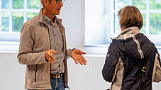 Zwei Personen im Gespräch an einem Stehtisch mit Schild "Bürgerenergiegenossenschaft Barnimer Energiewandel"