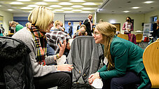 Zwei Frauen sitzen zusammen und unterhalten sich im Hintergrund einer Veranstaltung