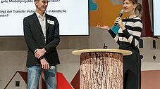 Zwei Personen auf Bühne bei Smart Country Brandenburg, eine spricht an Rednerpult, Präsentation im Hintergrund