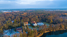 Luftaufnahme eines Gebäudekomplexes inmitten von Herbstwald an einem See